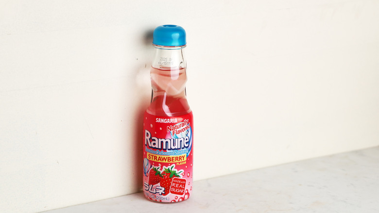 Soft pink soda bottle pictured against a white wall