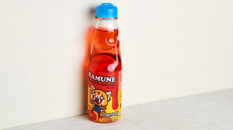 Bright orange Ramune soda against a wall