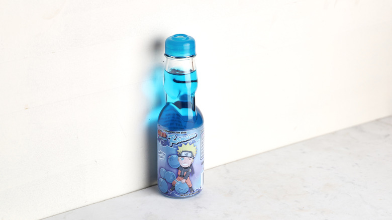 Bright blue soda bottle against the wall