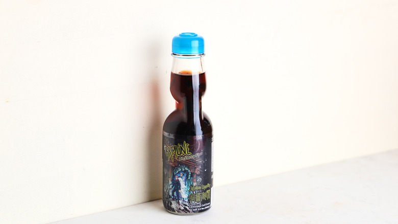 Dark purple soda in a glass bottle alone