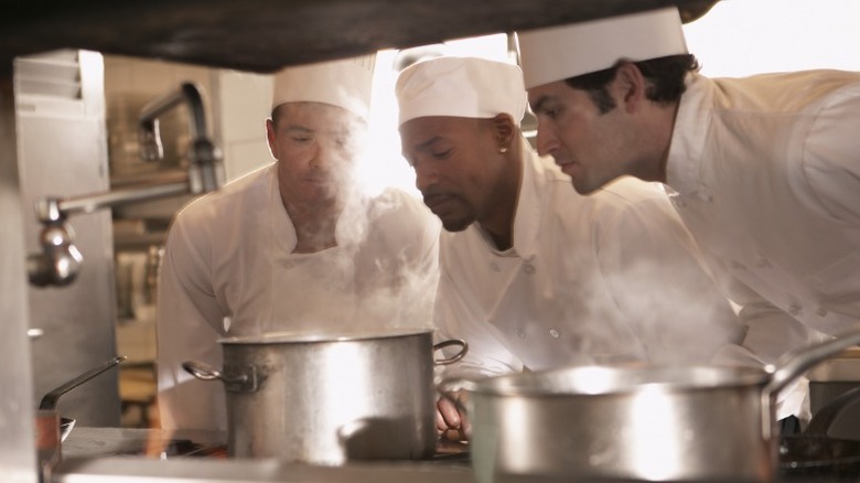 Three chefs smelling hot dish