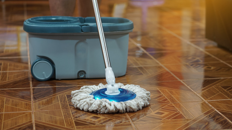 A mop and bucket on a parquet floor