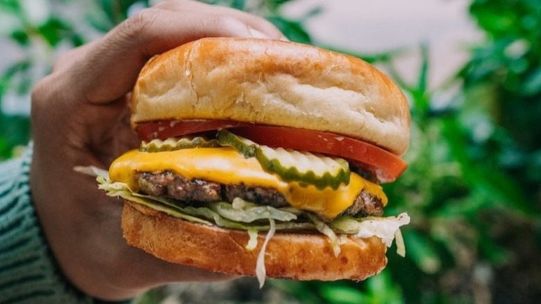 Hand holding a hamburger from Zinburger.