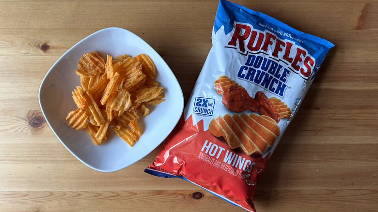 Double Crunch Hot Wings bag with a bowl of chips on a wooden table