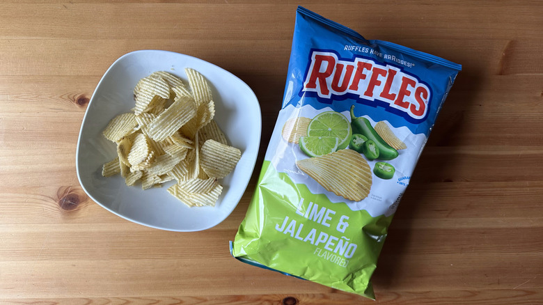 Lime and Jalapeño Ruffles bag with a bowl of chips on a wooden table