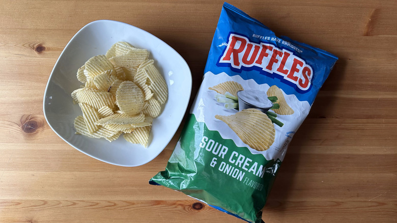 Sour Cream and Onion Ruffles bag with a bowl of chips on a wooden table