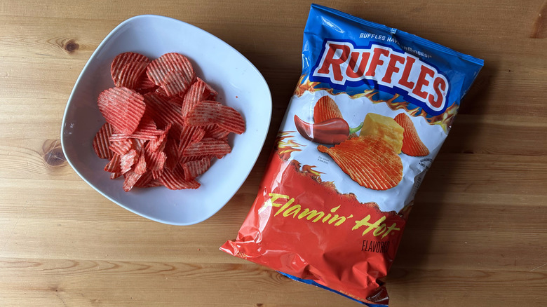 Flamin' Hot Ruffles bag with a bowl of chips on a wooden table