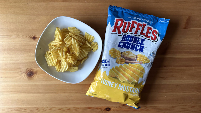 Double Crunch Honey Mustard Ruffles bag with a bowl of chips on a wooden table