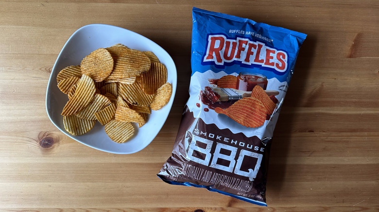 Smokehouse BBQ Ruffles bag with a bowl of chips on a wooden table