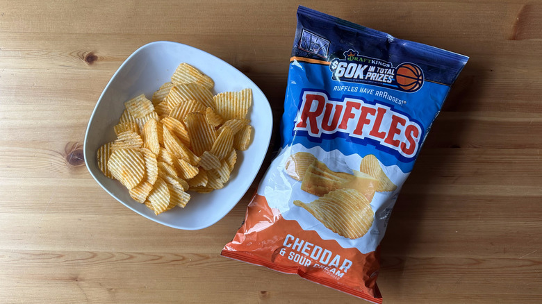 Cheddar and Sour Cream Ruffles bag with a bowl of chips on a wooden table