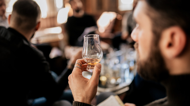 a man looking at a whisky tasting glass