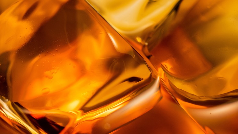 close up of caramel-colored whisky and ice