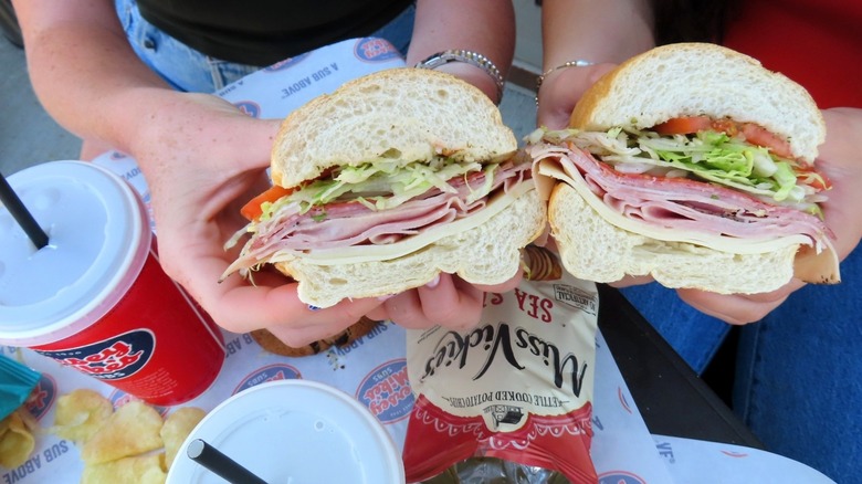 Two customers holding cut sandwiches