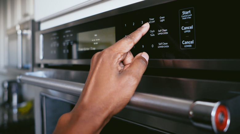 Person pressing a button on an electric oven