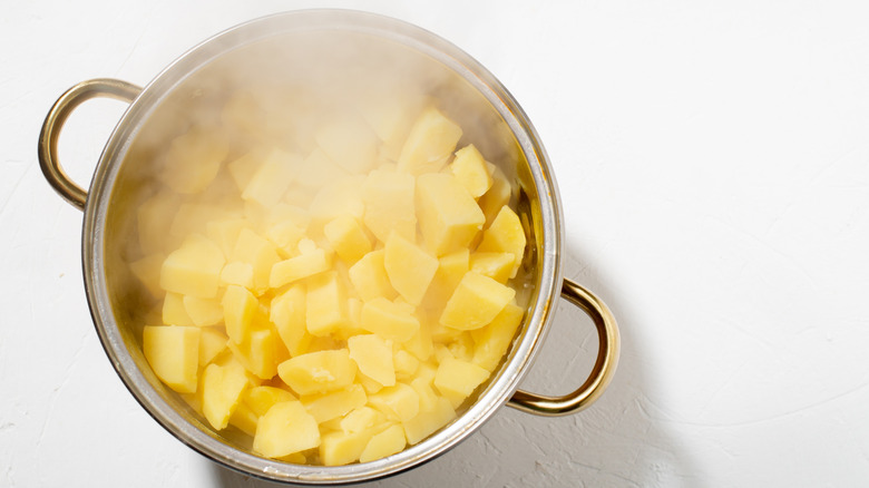Metal pot of steaming boiled potatoes