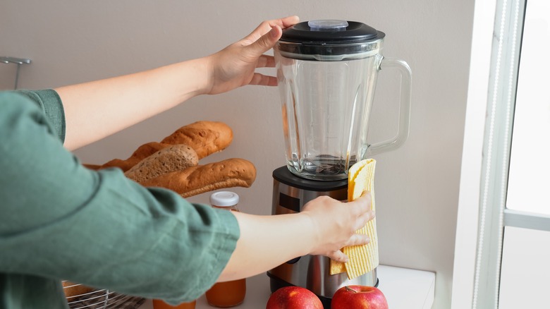 Person cleaning a blender with a cloth