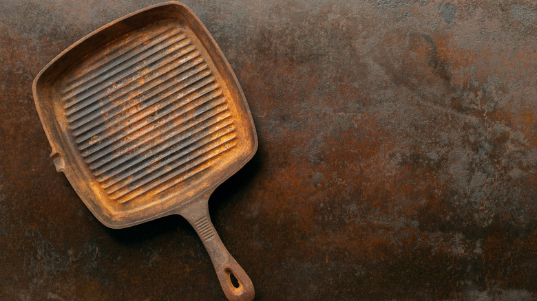 heavily-rusted cast iron grill pan on dark granite background