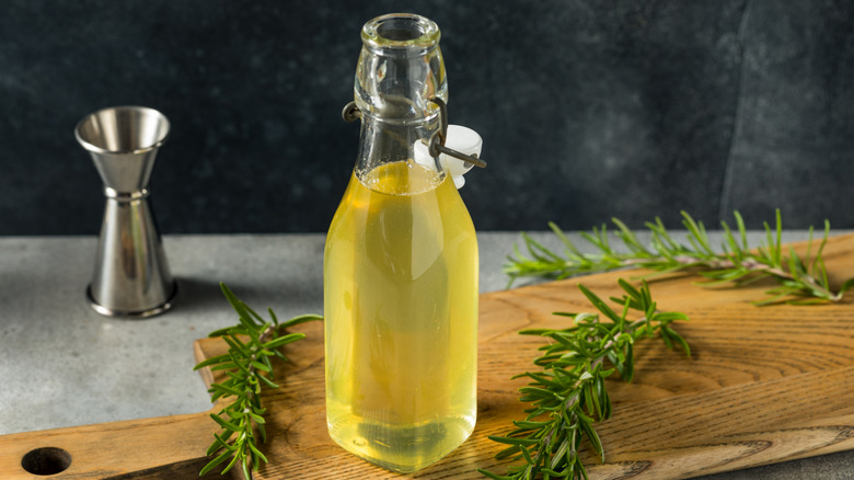 homemade yellow simple syrup on wood cutting board with rosemary sprigs