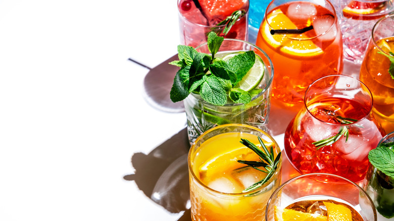 vibrant, colorful assortment of cocktails with fruit and herb garnishes on white background