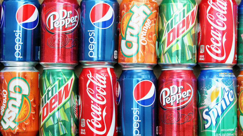 a dozen stacked cans of assorted name-brand sodas