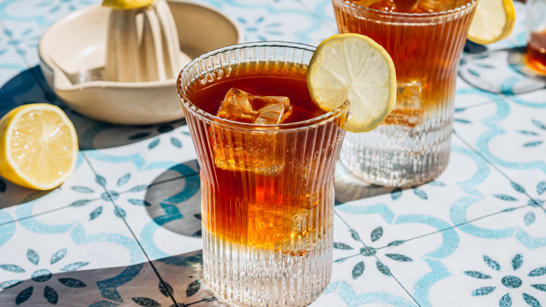 coffee spritzer in small glass with lemon slice garnish and citrus reamer in background