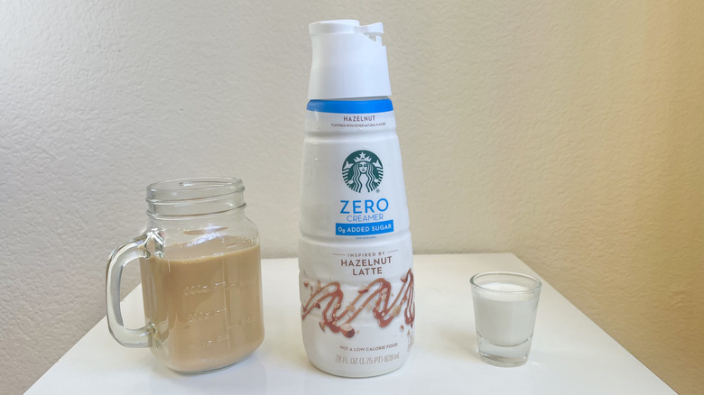 Starbucks Hazelnut Latte Zero Creamer in bottle, shot glass, and jar of coffee