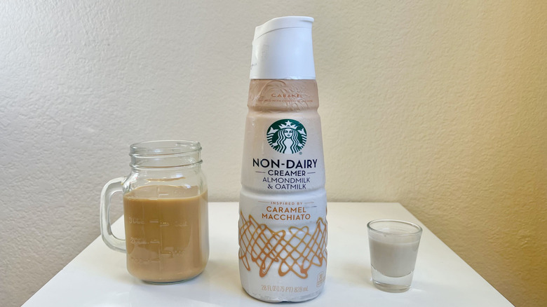 Starbucks Non-Dairy Caramel Macchiato creamer in bottle, shot glass, and jar of coffee