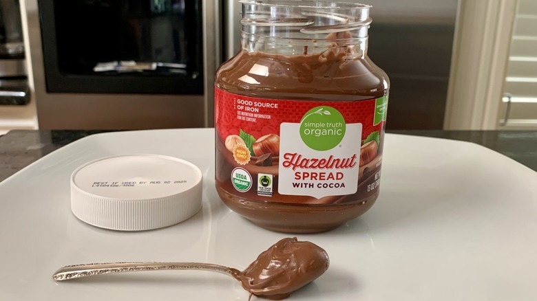 Simple Truth Organic Hazelnut Spread with Cocoa next to spoonful of it