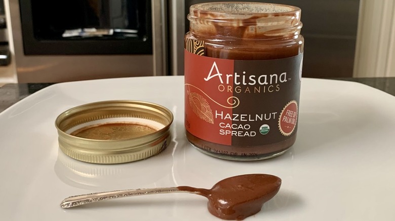 Open jar of Artisana Organics Hazelnut Cacao Spread with spoonful of it