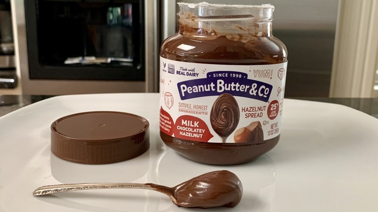 Opened jar of Peanut Butter & Co Milk Chocolatey Hazelnut Spread with spoonful