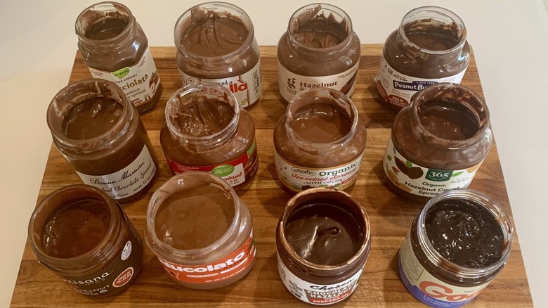 group of open jars of hazelnut spreads on a cutting board