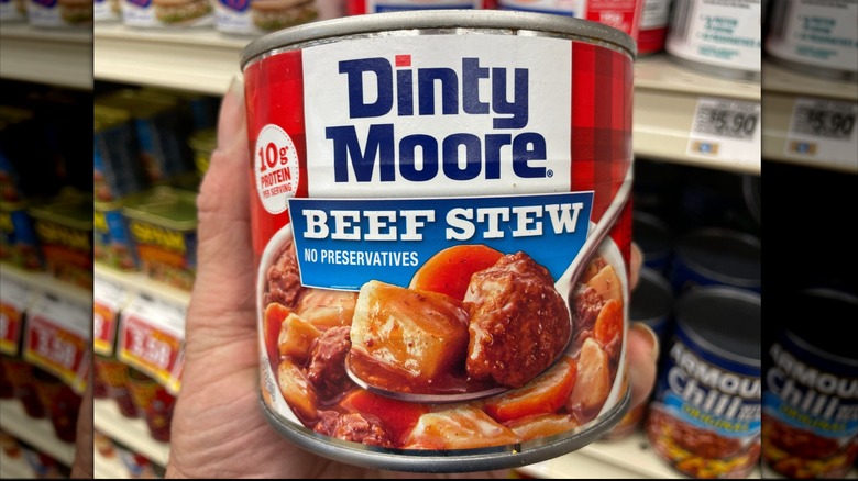 Hand holding a can of Dinty Moore Beef Stew at the store