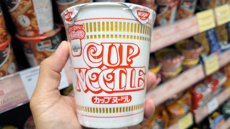 Hand holding a Nissin Cup of Noodles container at the store