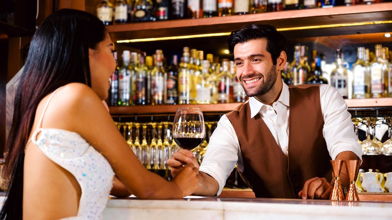 Bartender handing wine to woman