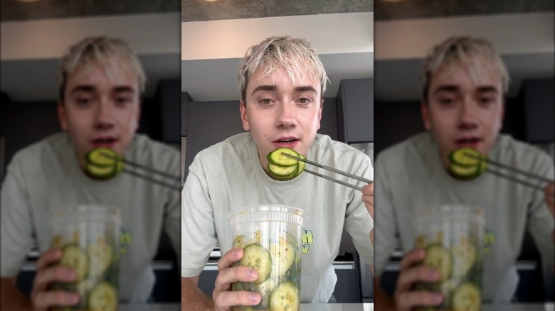 Man eating cucumber salad from plastic tub with chopsticks