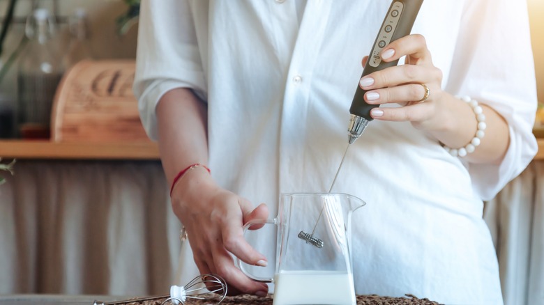 Person using handheld milk frother