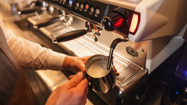 Barista frothing pitcher of milk