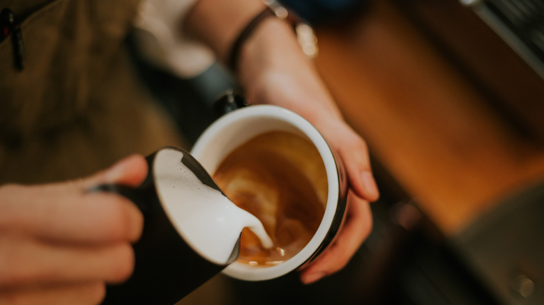 Pouring steamed milk into coffee