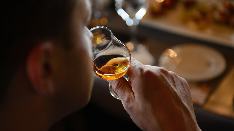 Person sniffing whiskey from a glass