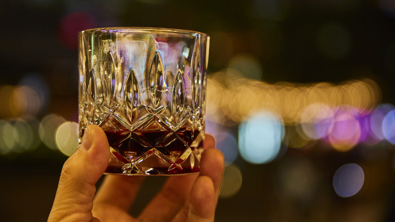 Person holding up whiskey glass