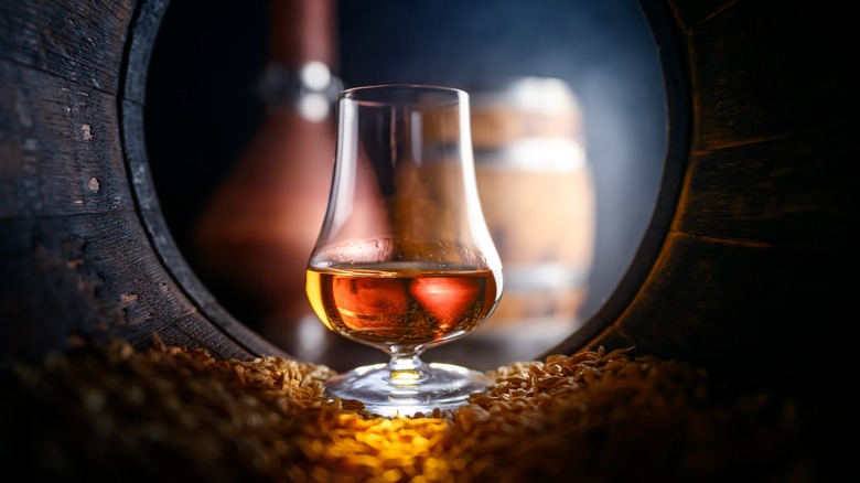 Whiskey glass inside a barrel with grains