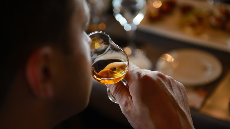 person sniffing bourbon in glass