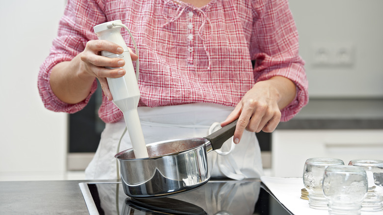 woman using immersion blender 