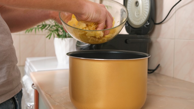 putting cut potatoes into a slow cooker