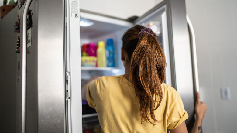 woman reaching into refrigerator