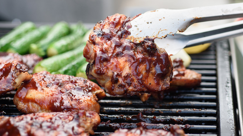 tongs flipping chicken on grill