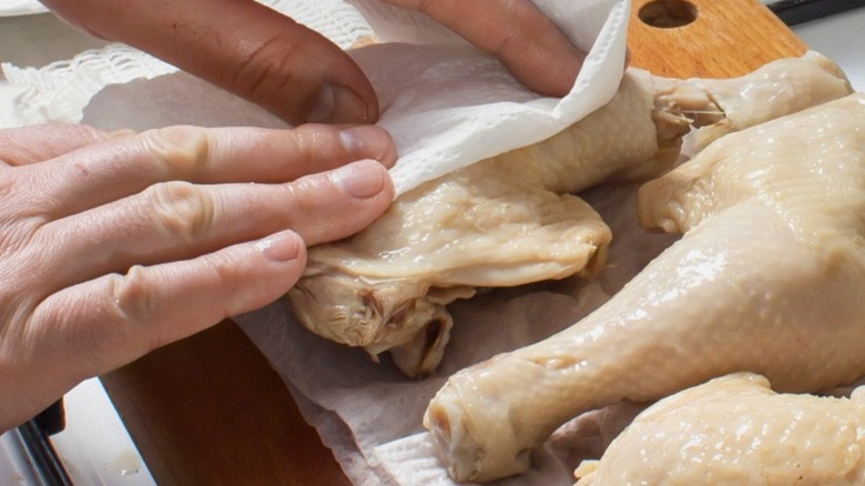 patting raw chicken with towel