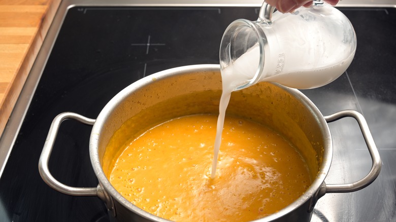 Coconut milk being poured into soup