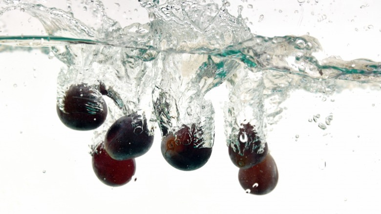 Purple grapes dropped into water