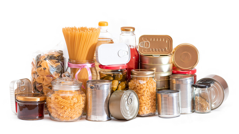 Pile of canned foods and jarred grains isolated on white background